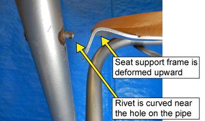 Photo showing the seat support frame distorted upward and the rivet curved at the end near the hole on the pipe.