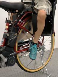 Photo of a child seated on a child bike seat. The photo shows a boy aged 9 when his legs are dangled and closer to the inside.