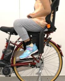 Photo of a child seated on a child bike seat.The photo shows a girl aged 10 when her feet are on the footrest.