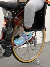 Photo of a child seated on a child bike seat.The photo shows a girl aged 10 when her legs are dangled and closer to the inside.