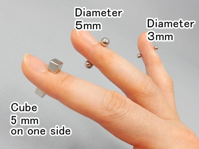 Photo shows that two magnetic balls attract to one another through a finger.