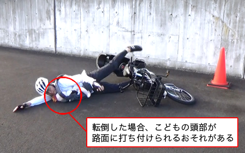写真1枚目。こどもを抱っこしたまま運転中の大人も自転車と共に転倒している様子を表している。